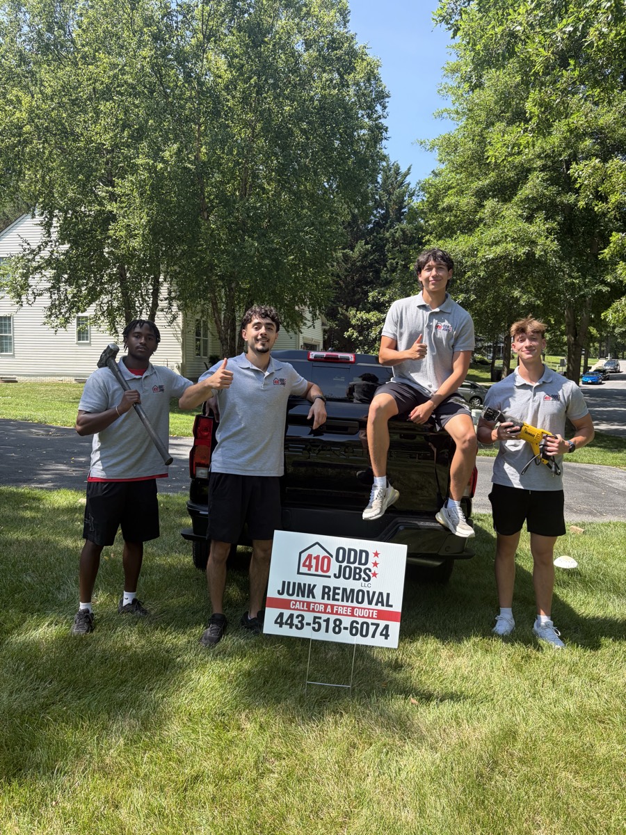 Ahmad and the 410 Odd Jobs crew beside a pickup truck with the company junk removal yard sign