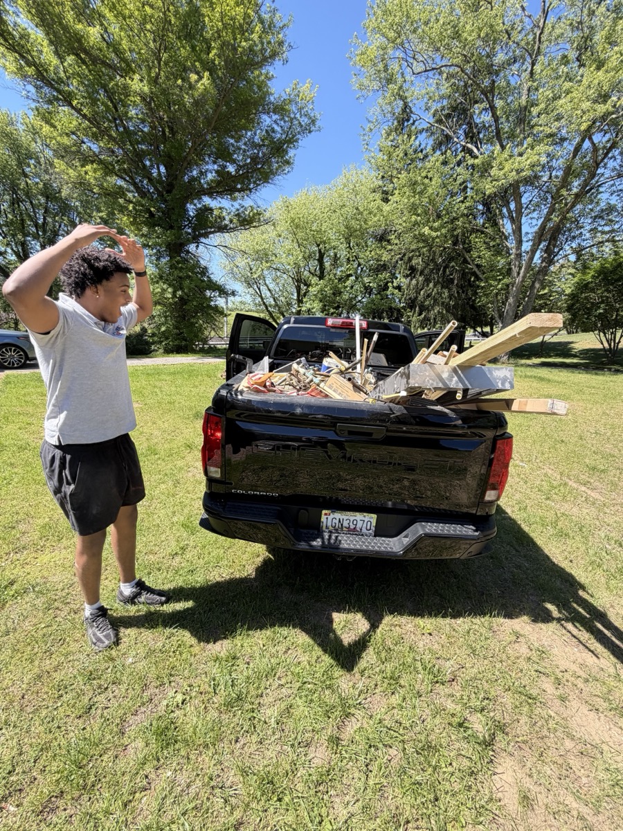 410 Odd Jobs team member beside a pickup truck loaded with lumber and debris