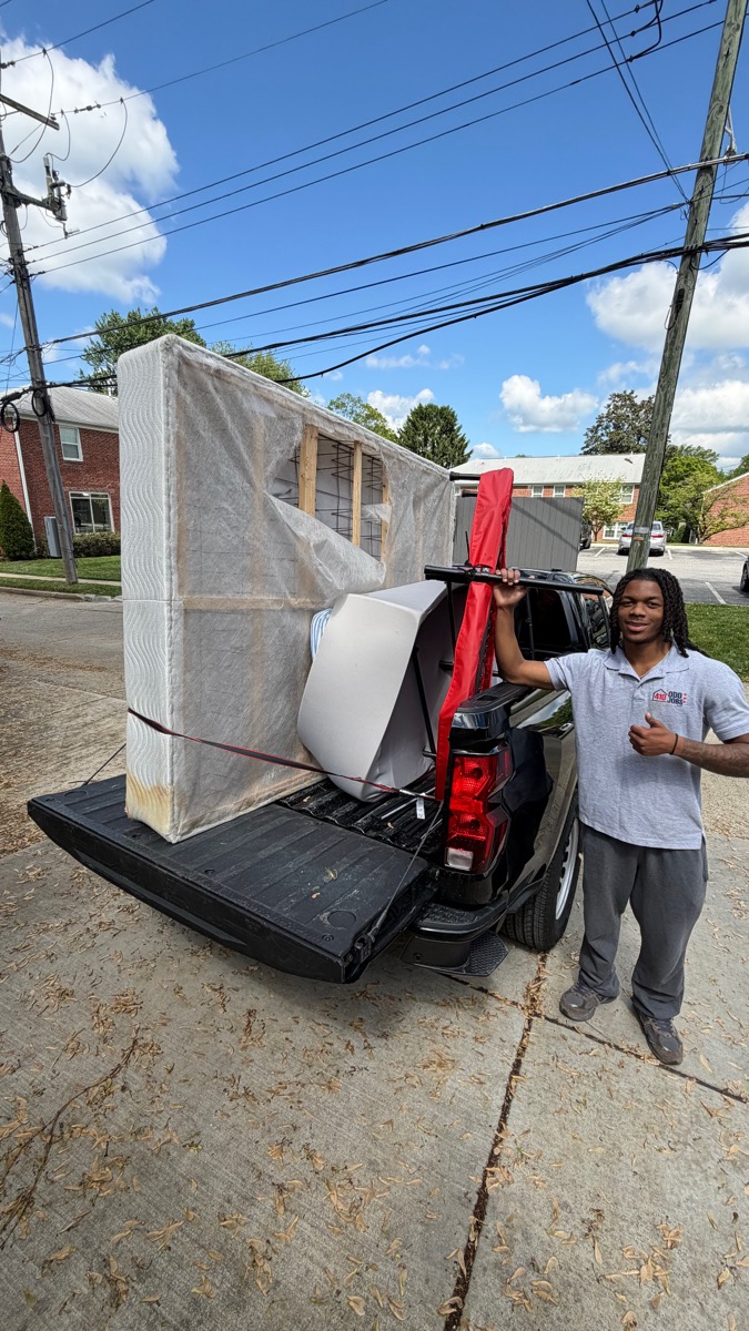 410 Odd Jobs team member beside a pickup truck with wrapped furniture